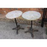 A pair of mottled marble circular topped bistro tables, on cast iron supports, 19" dia