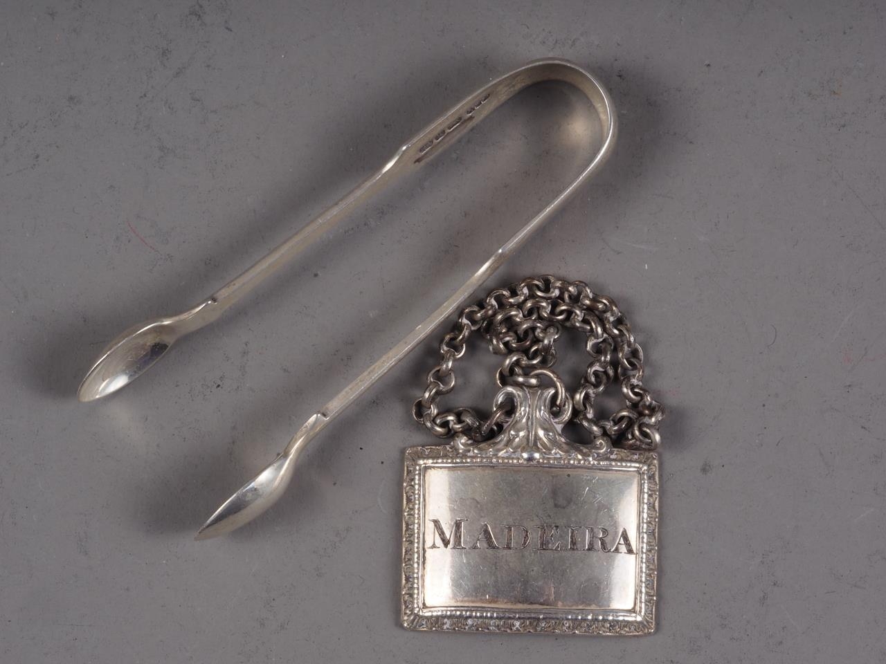 A silver plated Madeira decanter label and a pair of silver sugar tongs