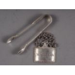 A silver plated Madeira decanter label and a pair of silver sugar tongs