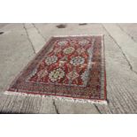 A Hamadan type rug with numerous shaped medallions and on a rust ground and multi-bordered in