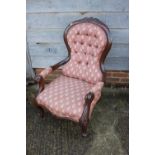 A carved walnut showframe open armchair, button upholstered in a Paisley fabric, on scroll supports