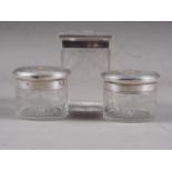 Three dressing table jars with engine turned and yellow metal mounted silver lids