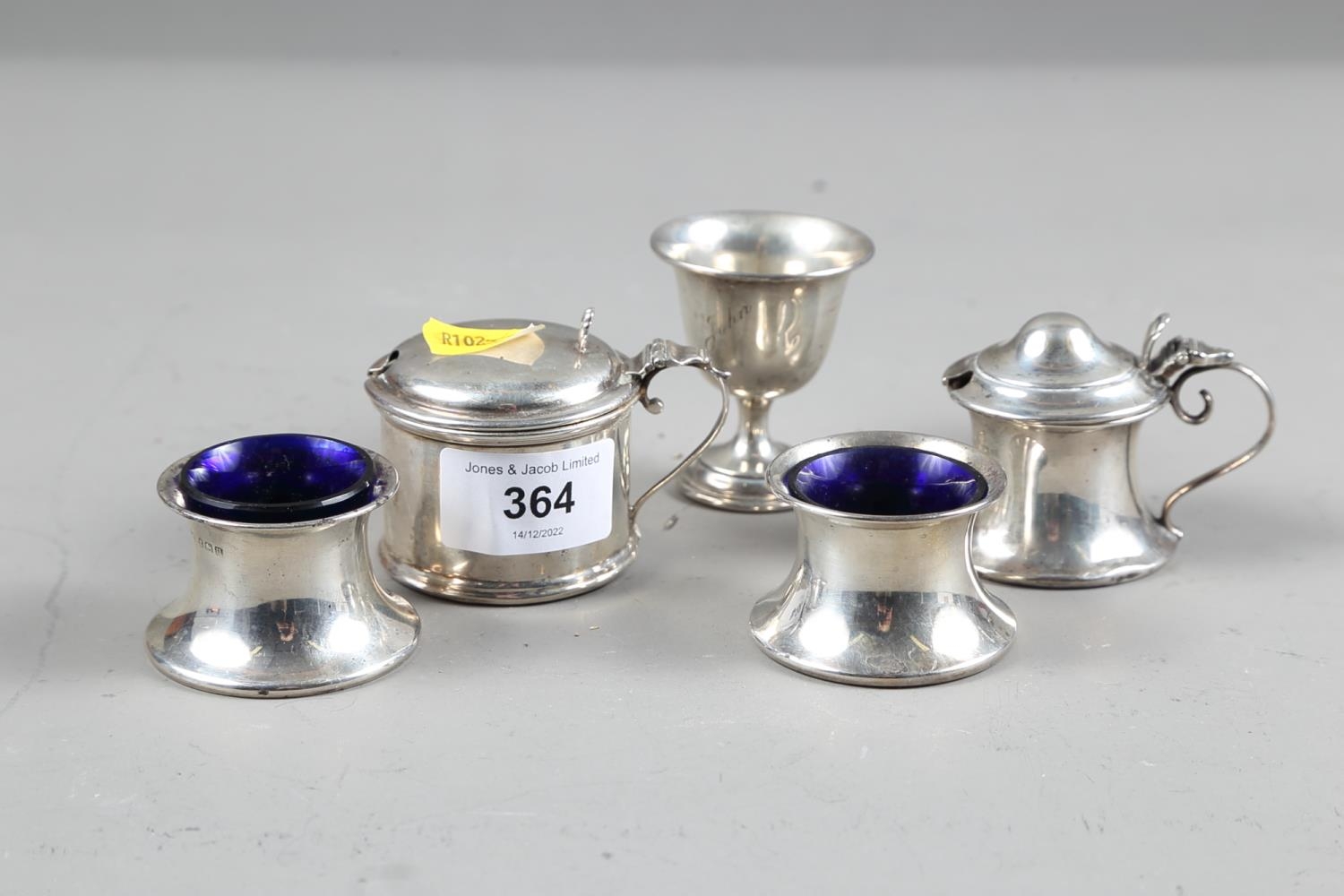 A pair of silver salt cellars with blue glass liners, a similar mustard pot with blue glass