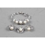 A white metal and pearl bracelet, a matching pendant and two similar rings, 27.9g gross