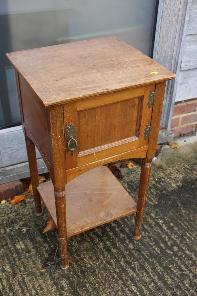 An early 20th century walnut bedside cupboard enclosed one door over undertier, on turned