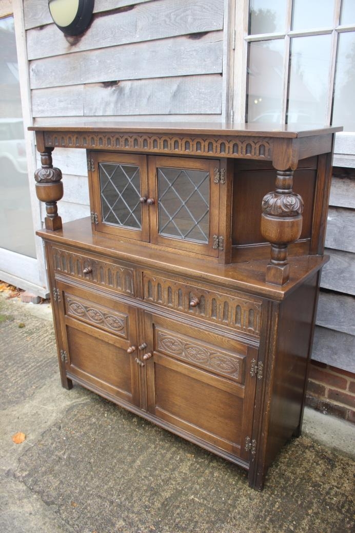 A carved oak court cupboard, the upper section enclosed leaded lattice glazed door over two