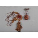 A carved agate pendant necklace, decorated horse, and a carved fruitwood pendant, decorated two