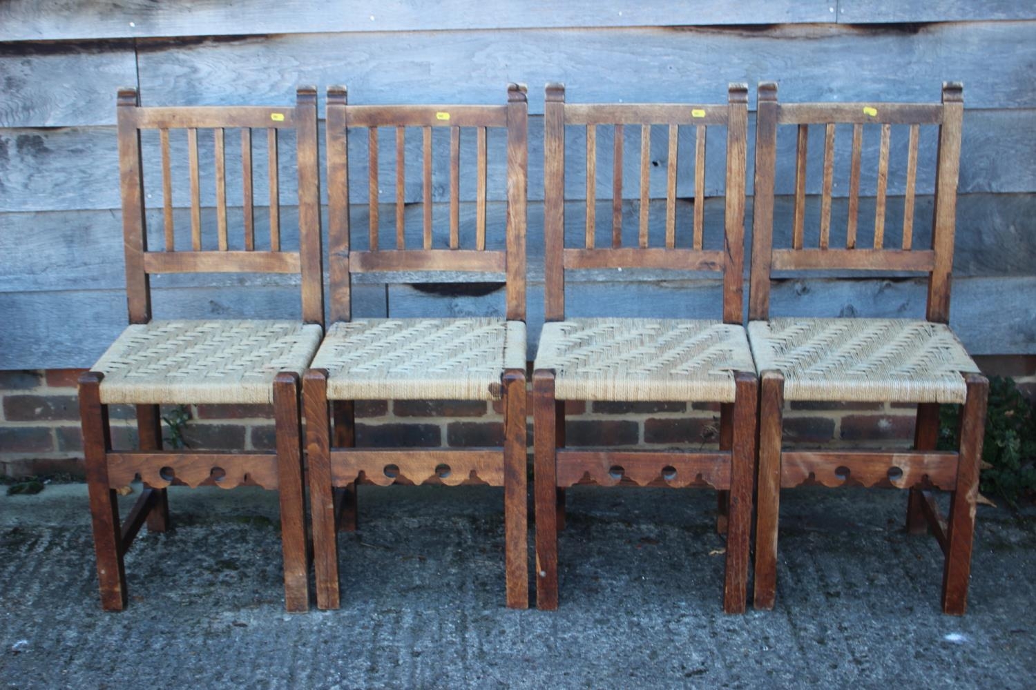 A set of four Spanish oak vertical rail back dining chairs with string seats, on stretchered