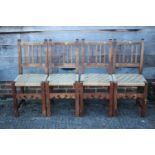 A set of four Spanish oak vertical rail back dining chairs with string seats, on stretchered