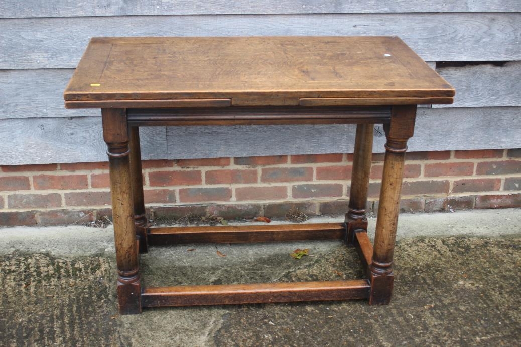 An oak draw leaf table of 17th century design, on turned column and stretchered supports, 41" wide x