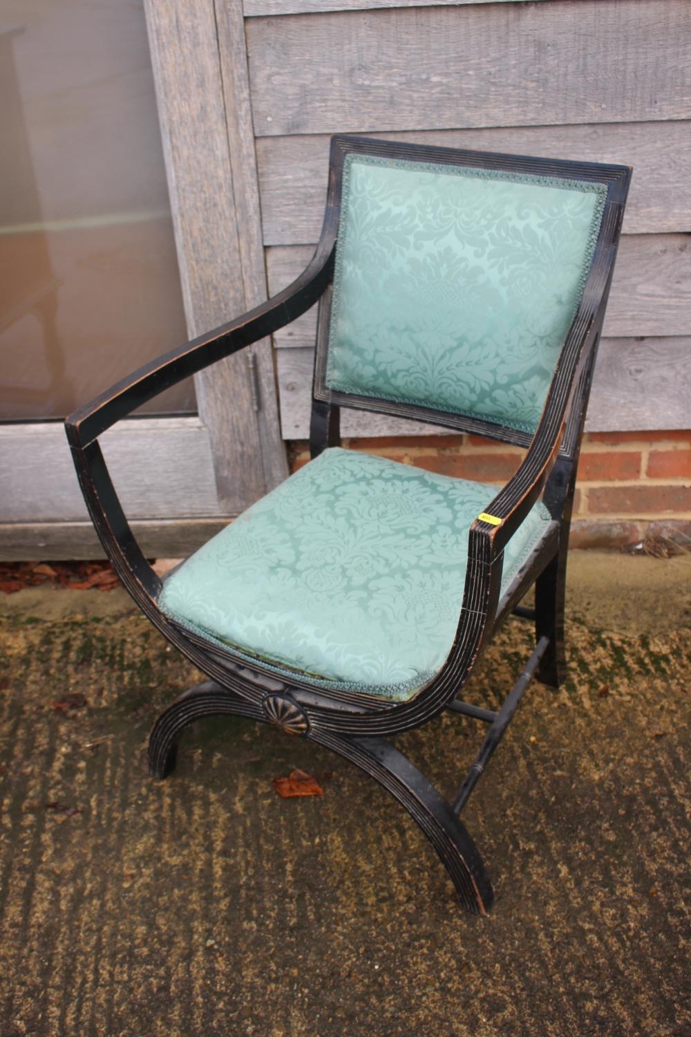 A late 19th century ebonised reeded 'X' frame elbow chair with padded seat and back