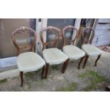 A set of four Victorian grained as rosewood loop back dining chairs with stuffed over seats,