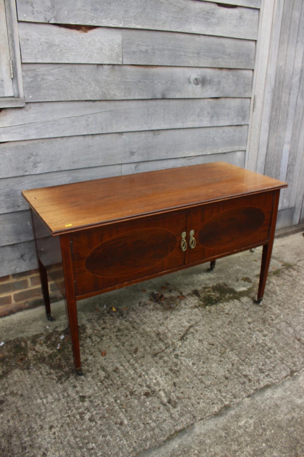 An Edwardian mahogany and banded side cupboard/carving table enclosed two doors, on square taper