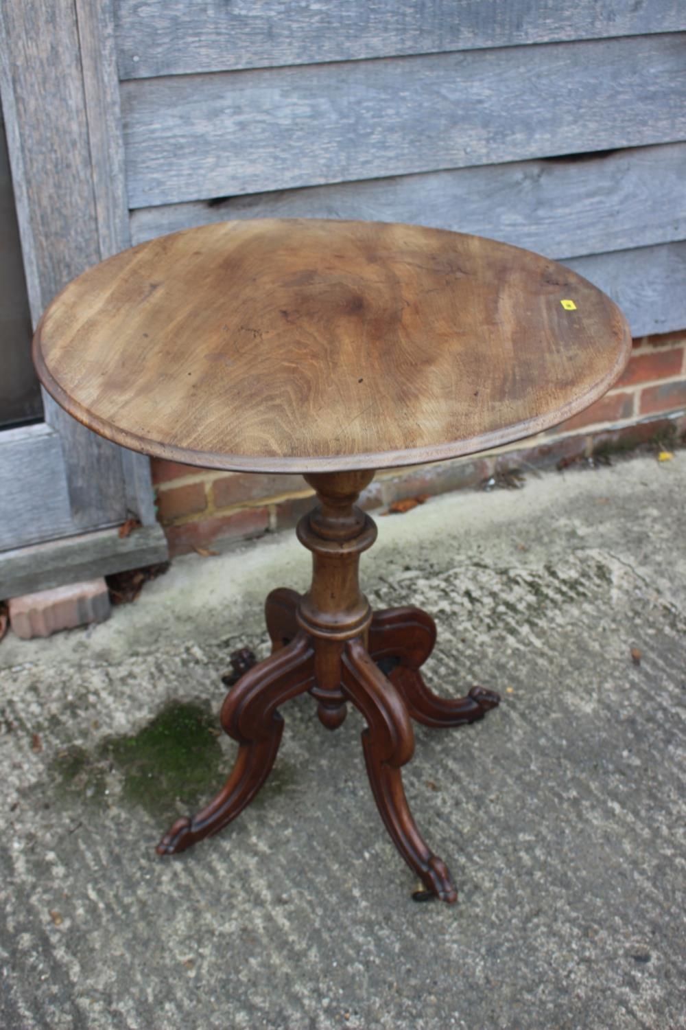 A 19th century walnut circular tilt top occasional table, on turned column and quadruple scroll