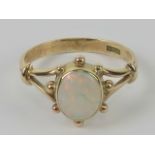 A contemporary 9ct gold and opal ring, the central oval cabachon having good multi colour fire,