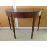 Ad Edwardian mahogany demi-lune table raised over square tapering legs, measuring 96 x 47 x 70cm.