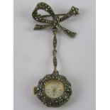 A silver and marcasite watch suspended from a brooch in the form of a bow, London import hallmark,