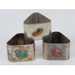 A set of three HM silver Modernist design triangular napkin rings each set with a different oval