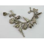 A charm bracelet with a large selection of silver and white metal charms upon including Noahs ark,