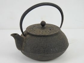 An oriental cast iron teapot having raised floral decoration upon, swing handle,
