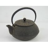 An oriental cast iron teapot having raised floral decoration upon, swing handle,