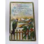 A vintage Christmas postcard featuring bird upon fence with snow covered bridge and building beyond,