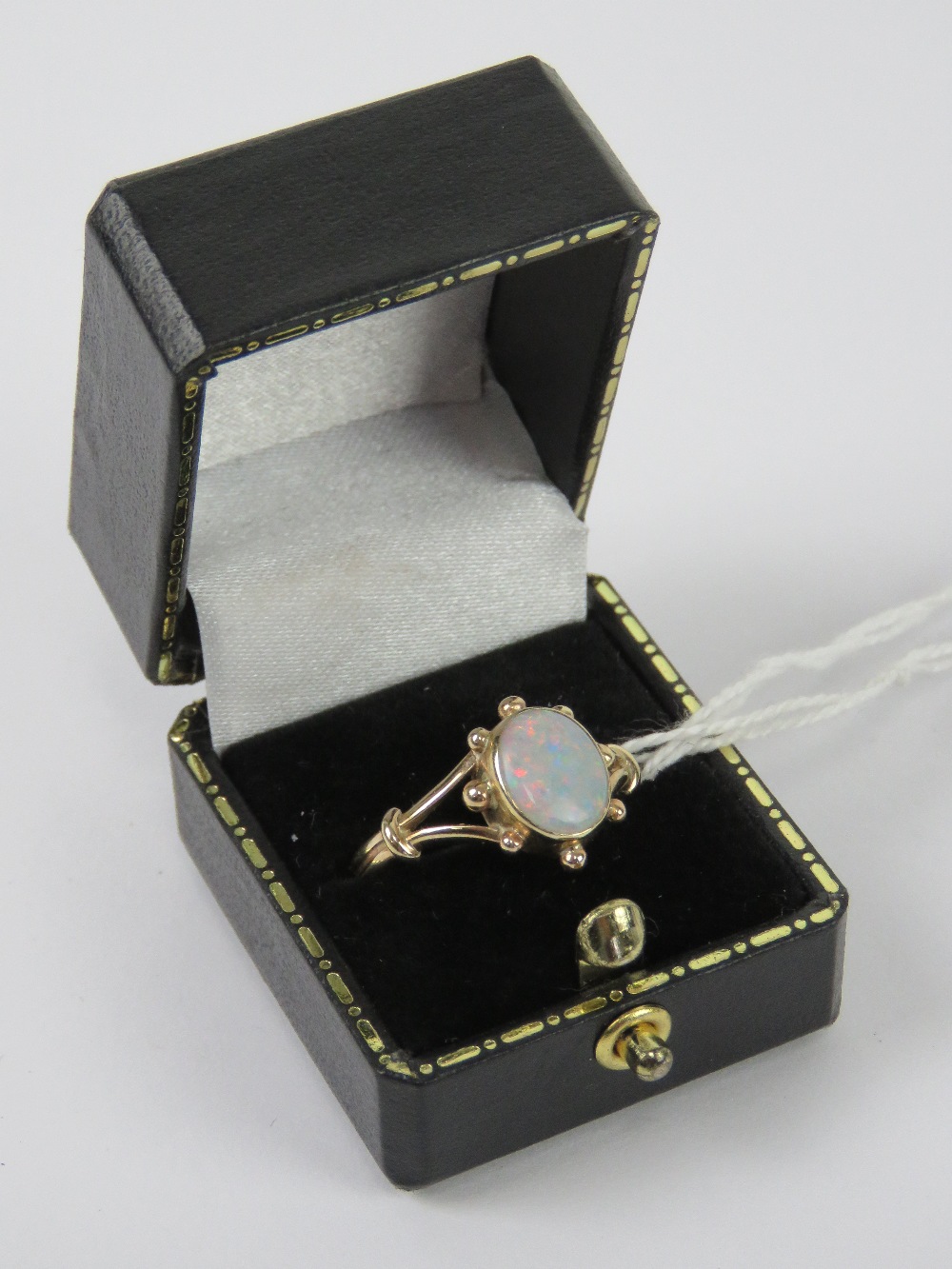 A contemporary 9ct gold and opal ring, the central oval cabachon having good multi colour fire,