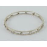 A hallmarked silver solid bangle having alternating square and round but white stones throughout,