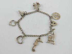 An HM silver charm bracelet having part padlock clasp and seven charms upon,