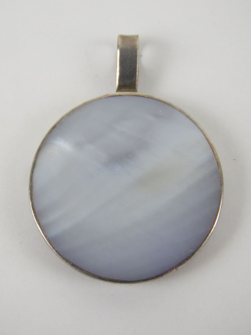 A mother of pearl and silver pendant of circular form, stamped 925, 3.8cm dia.