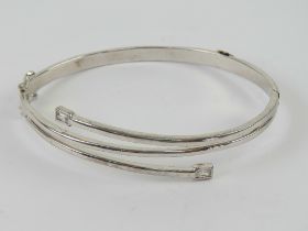 An HM silver hinged bangle having double safety clasp, wrap style having cz set terminals,