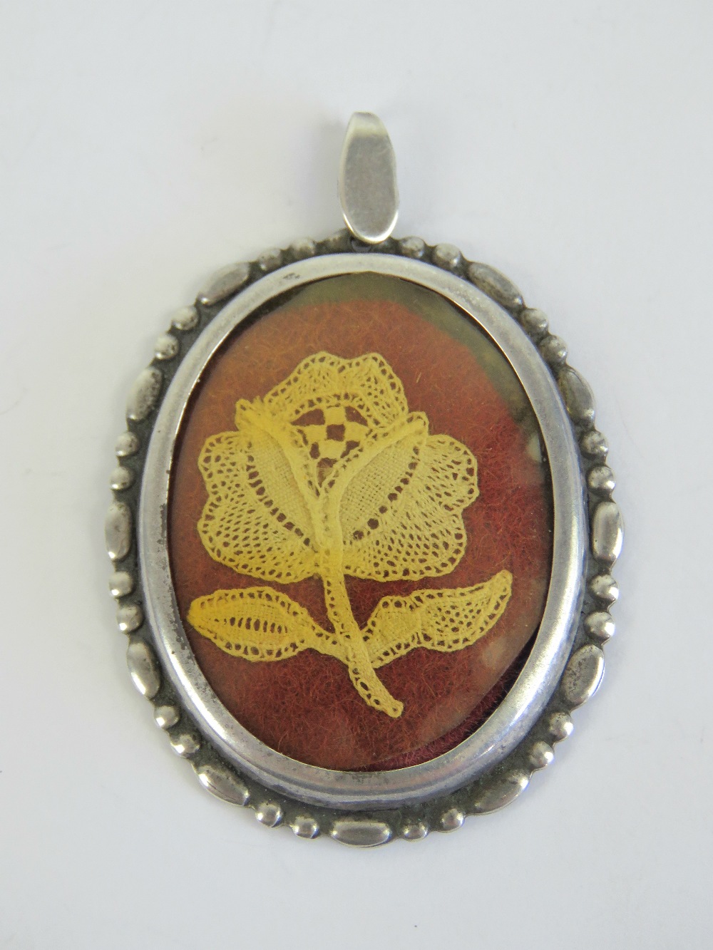 A HM silver pendant having lacework rose within, hallmarked for Birmingham 1981, 5.3cm in length.