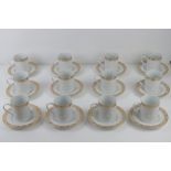 A set of twelve contemporary cream ground and gilded coffee mugs and saucers.