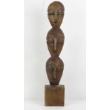 A carved wooden Totem in the form of three masks, standing 51.5cm high.