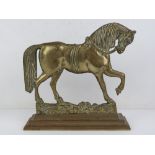 A heavy brass doorstop in the form of a horse, 24cm wide.