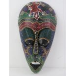 A carved and ebonised wall mask having Aboriginal type dot paint Pointillism decoration upon,