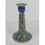 A ceramic candlestick having oriental style pattern in yellow and blue, standing 18cm high.