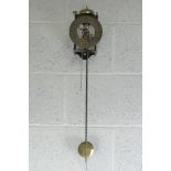 A contemporary wall clock having brass skeleton movement with weight and pendulum.