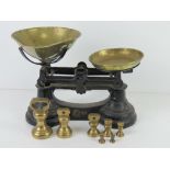 A set of black painted balance scales with brass pans and set of brass weights 1/4oz to 1lb.