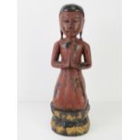 A painted wooden carving of a praying figure, 41cm high.