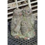 A pre-cast and painted garden statue of three owls standing 32cm high.