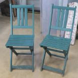 A pair of green painted wooden bistro chairs.