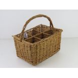 A wicker wine bottle holder having six sections and loop handle, 35 x 24cm.