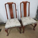 A pair of mahogany hall chairs having padded seats covered in damask fabric.