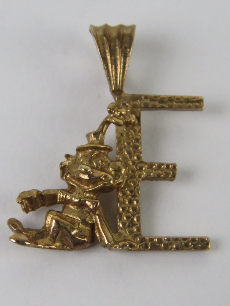 A 9ct gold pendant in the form of an 'E' with clown figure leaning upon, 2cm in length, 1.2g.