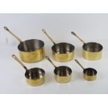 A set of six graduated brass saucepan.