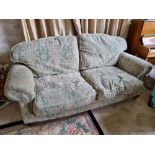 A Victorian style two seater scroll arm settee raised over short legs terminating in brass castors.