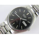 A Seiko SQ stainless steel wristwatch with original strap, black dial with day and date apertures.