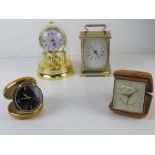 A Smiths Empire travel clock together with another travel clock and two small mantel clocks.