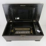 A Swiss music box lid lifting to reveal cylinder and comb within, two teeth deficient,